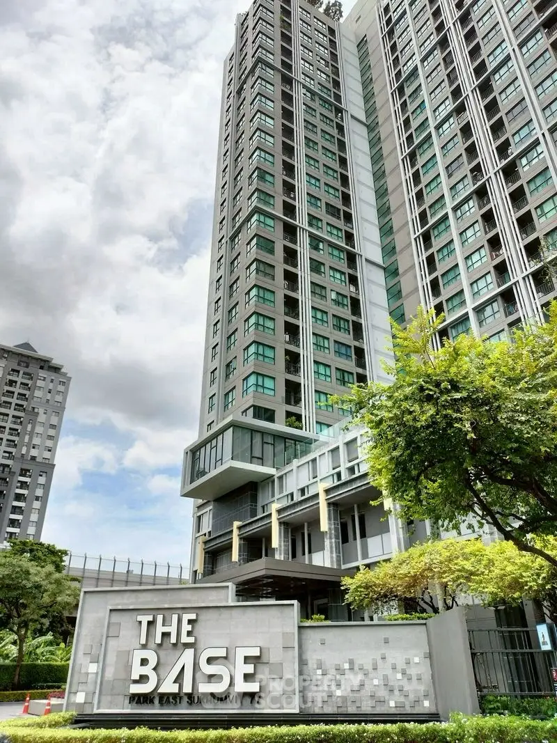 Modern high-rise condominium with lush greenery and elegant entrance signage.