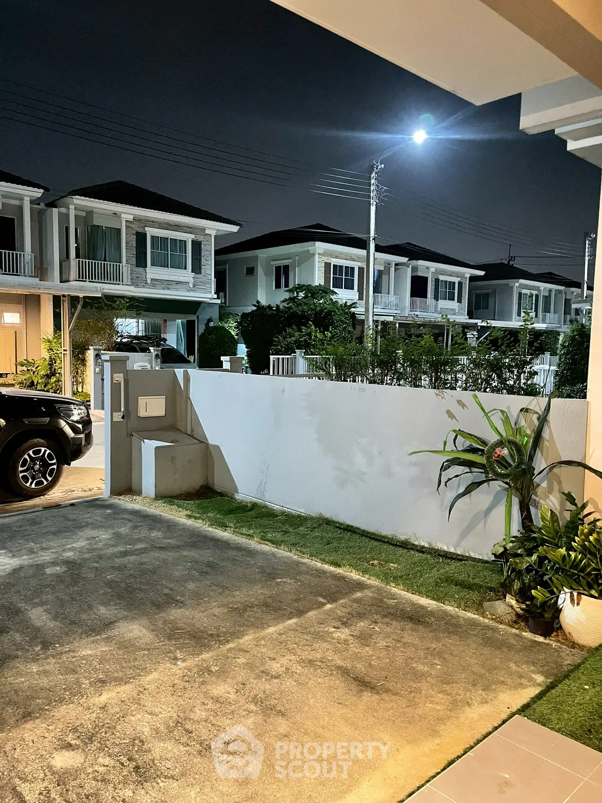 Charming suburban neighborhood with modern houses and well-maintained gardens at night.