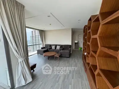 Spacious modern living room with stylish furniture and large windows offering city views.