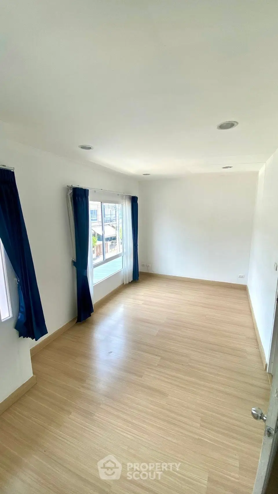 Spacious empty room with large windows and wooden flooring, perfect for customization.