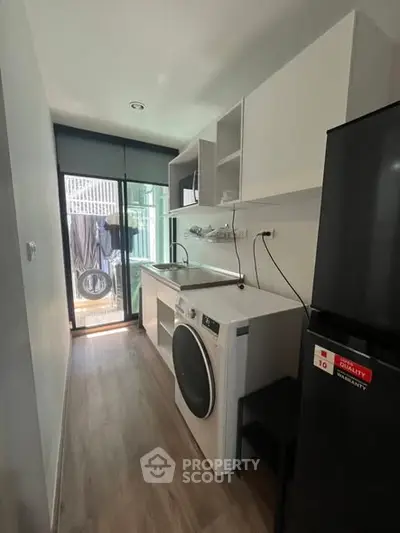 Modern kitchen with washing machine and sleek cabinetry in compact layout