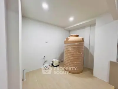 Spacious utility room with large water tank and modern lighting, ideal for storage or equipment setup.