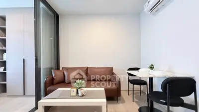 Modern living room with brown leather sofa and dining area in open layout apartment.
