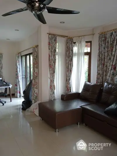 Spacious living room with elegant curtains and modern brown leather sofa