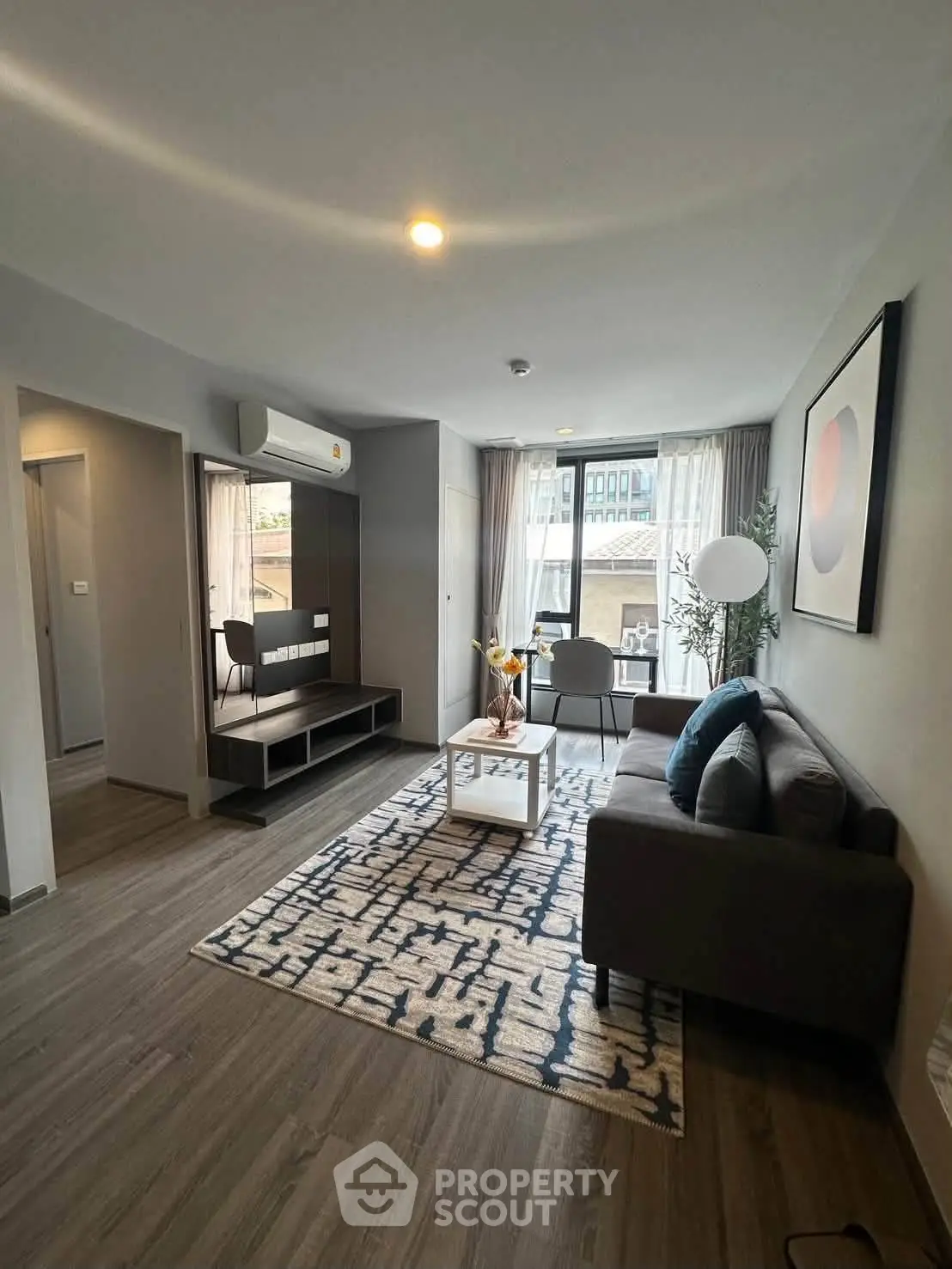 Modern living room with stylish decor and natural light, featuring a cozy sofa and elegant rug.