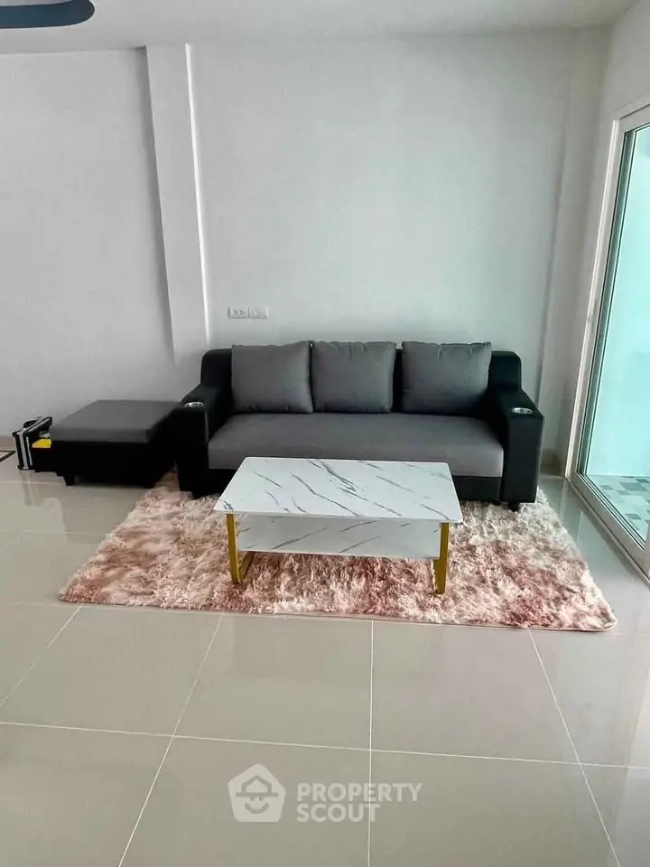 Modern living room with sleek sofa and marble coffee table on plush rug.