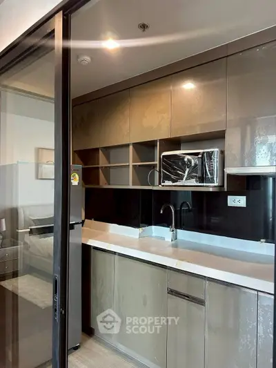 Modern kitchen with sleek cabinetry and built-in microwave in a stylish apartment
