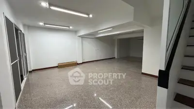 Spacious open-plan interior with modern lighting and staircase, ideal for versatile living or office space.