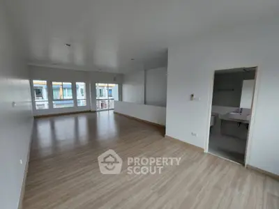 Spacious open-plan living area with wooden flooring and large windows for natural light.
