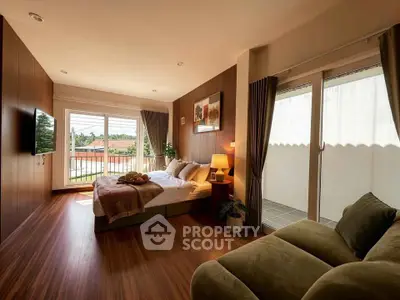 Spacious bedroom with balcony access and modern decor, featuring a cozy seating area and natural light.