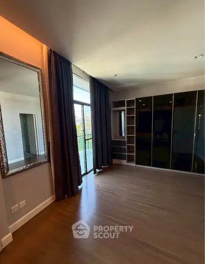 Spacious bedroom with large window and built-in wardrobe, featuring elegant wooden flooring and modern design.
