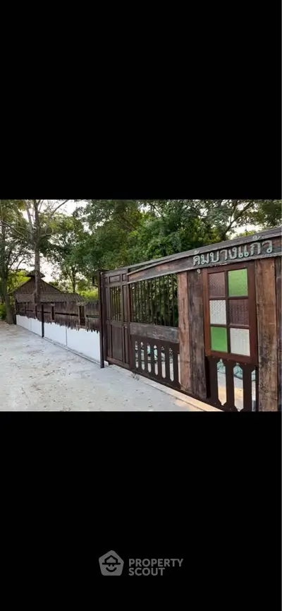 Charming rustic wooden gate entrance with lush greenery and serene surroundings.