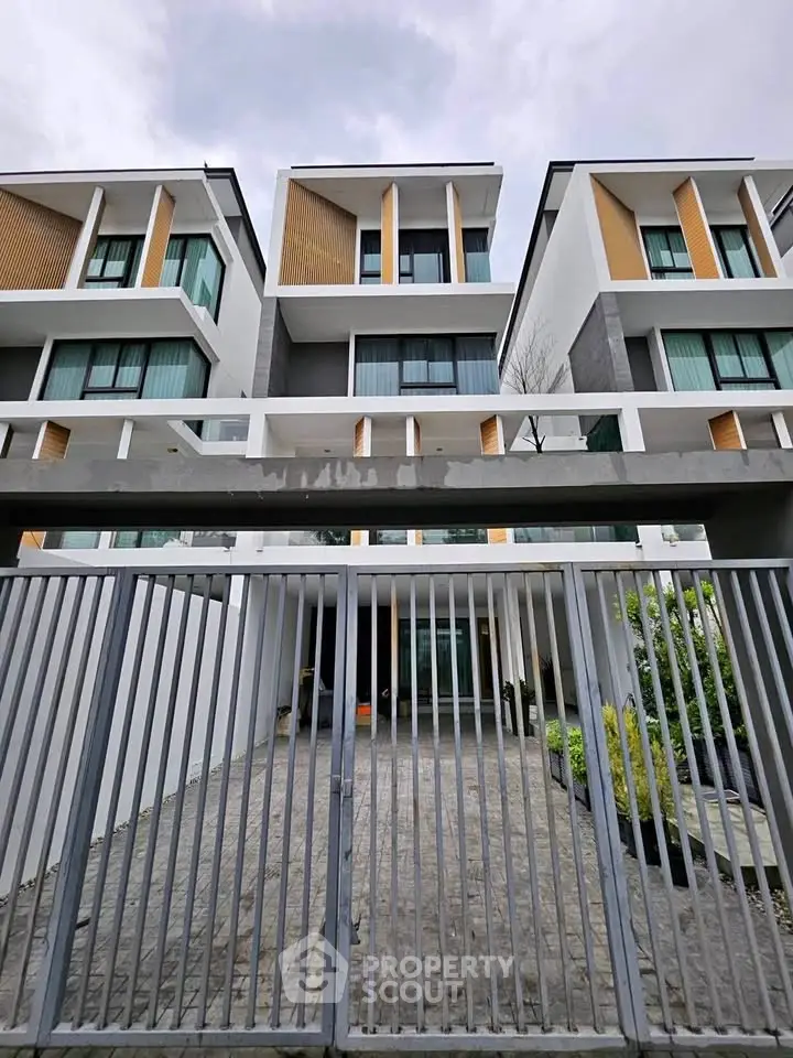 Modern multi-story residential building with sleek design and gated entrance.