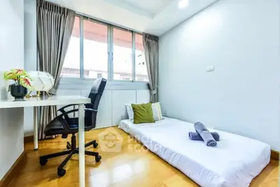 Cozy minimalist bedroom with floor mattress and study desk, perfect for urban living.