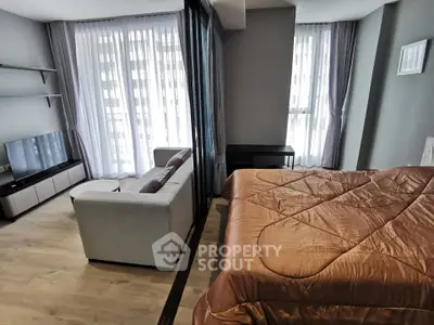 Modern studio apartment with cozy living area and stylish bedroom, featuring floor-to-ceiling windows.