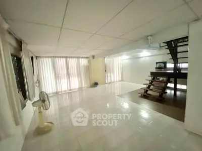 Spacious open-plan living area with tiled flooring and staircase, ideal for modern living.