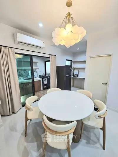 Modern dining area with elegant chandelier and open kitchen layout in a stylish apartment.