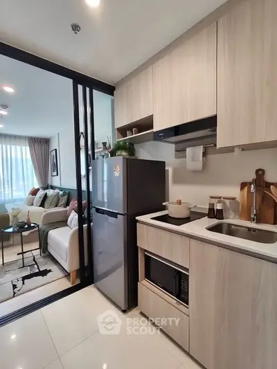 Modern kitchen with sleek cabinetry and open layout adjacent to cozy living room.