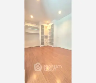 Spacious walk-in closet with wooden flooring and ample storage space.