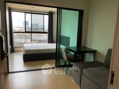 Modern studio apartment with glass partition, cozy seating, and city view.