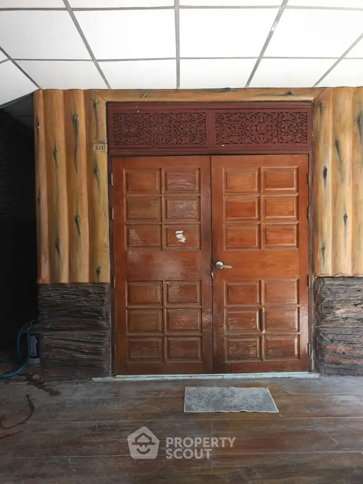 Elegant wooden entrance door with intricate carvings and natural wood finish