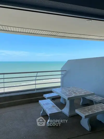 Stunning ocean view from a spacious balcony with stone table and benches, perfect for relaxation.