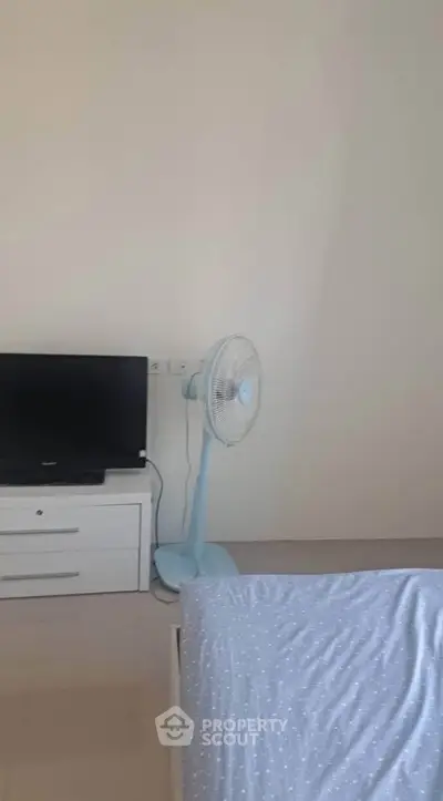 Cozy bedroom with TV and fan, perfect for relaxation.