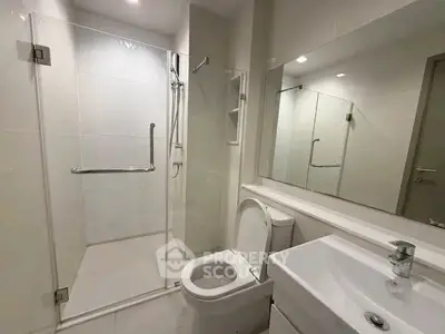 Modern bathroom with glass shower and sleek fixtures in a contemporary apartment.