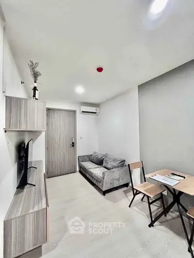 Modern living room with sleek furniture and minimalist design, featuring a cozy sofa and wall-mounted TV.