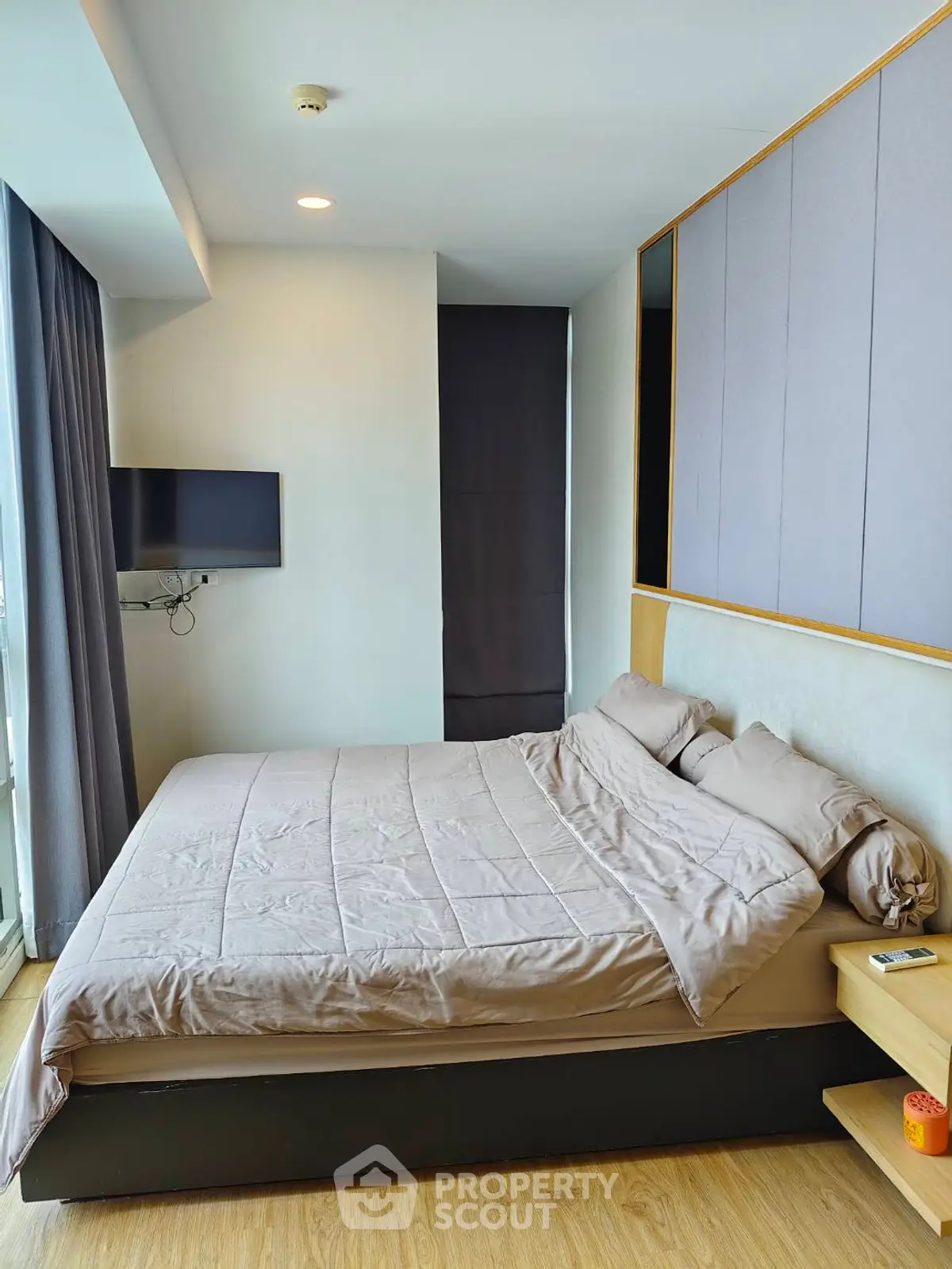 Modern bedroom with cozy bedding and wall-mounted TV in a stylish apartment.