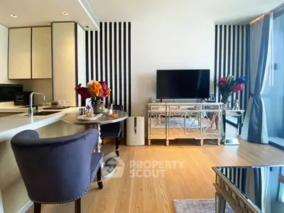 Modern living room with stylish decor and open kitchen layout, featuring elegant furniture and a large TV.