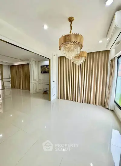 Luxurious living room with elegant chandeliers and large windows in a modern home.