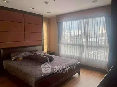 Spacious bedroom with large window and city view, featuring modern decor and cozy ambiance.