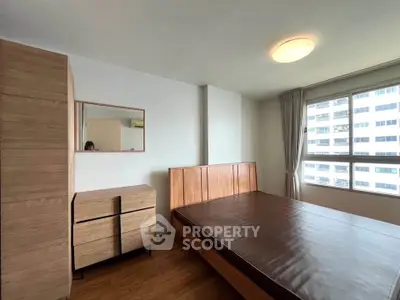 Spacious bedroom with wooden furniture and large window offering natural light