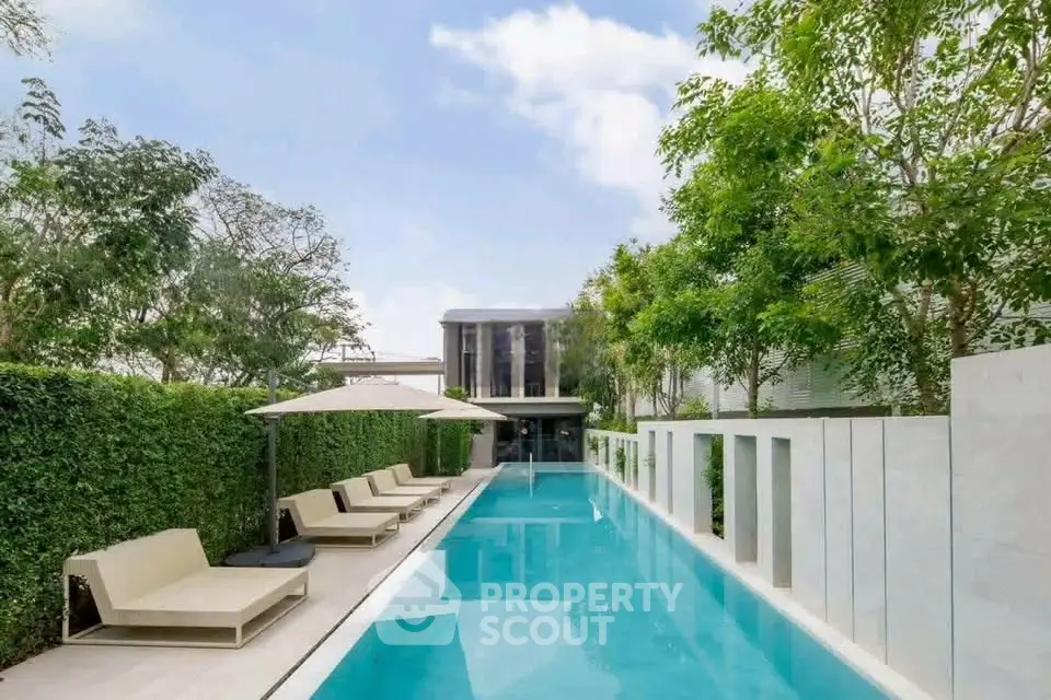 Luxurious modern poolside with sleek loungers and lush greenery, perfect for relaxation and entertainment.