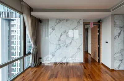 Spacious modern living room with marble accent wall and large windows offering city views.