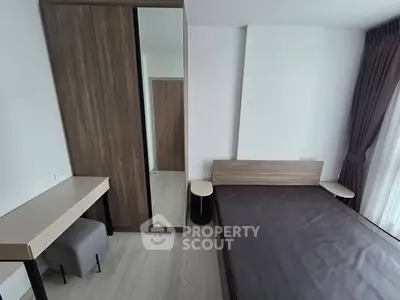 Modern bedroom with sleek furniture and large window for natural light.