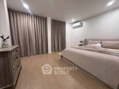 Spacious bedroom with modern decor and natural light, featuring elegant curtains and wooden flooring.