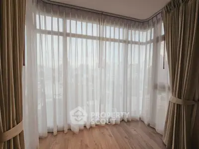 Spacious corner unit with floor-to-ceiling windows and elegant curtains offering a serene city view.