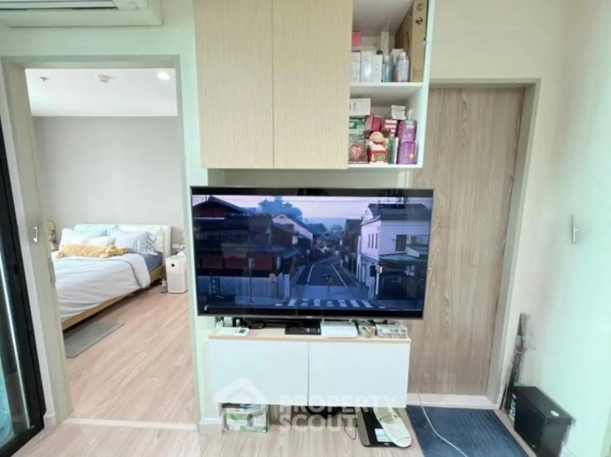Modern apartment interior with cozy bedroom and sleek living area featuring a wall-mounted TV and storage.