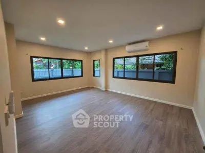 Spacious living room with large windows and modern flooring in a bright, airy home.