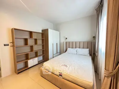 Spacious bedroom with modern furnishings and ample natural light, featuring a comfortable bed and stylish storage solutions.