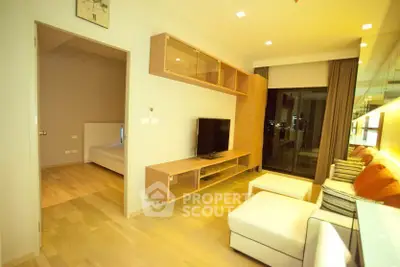 Modern living room with stylish furniture and open layout, featuring a large TV and wooden flooring.