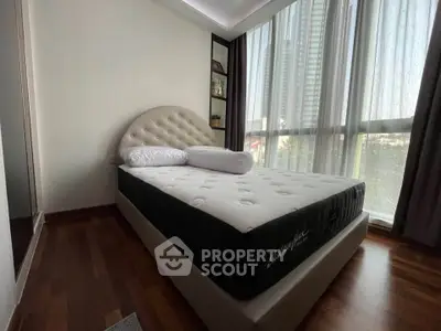 Cozy bedroom with modern design and large windows offering natural light and city views.