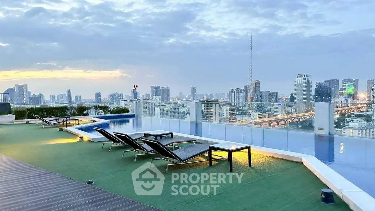 Stunning rooftop pool with panoramic city skyline views at sunset.