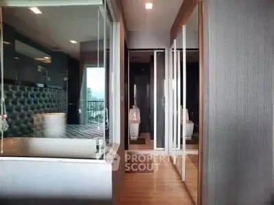 Modern bedroom with glass partition and mirrored closet doors, featuring sleek design and natural light.