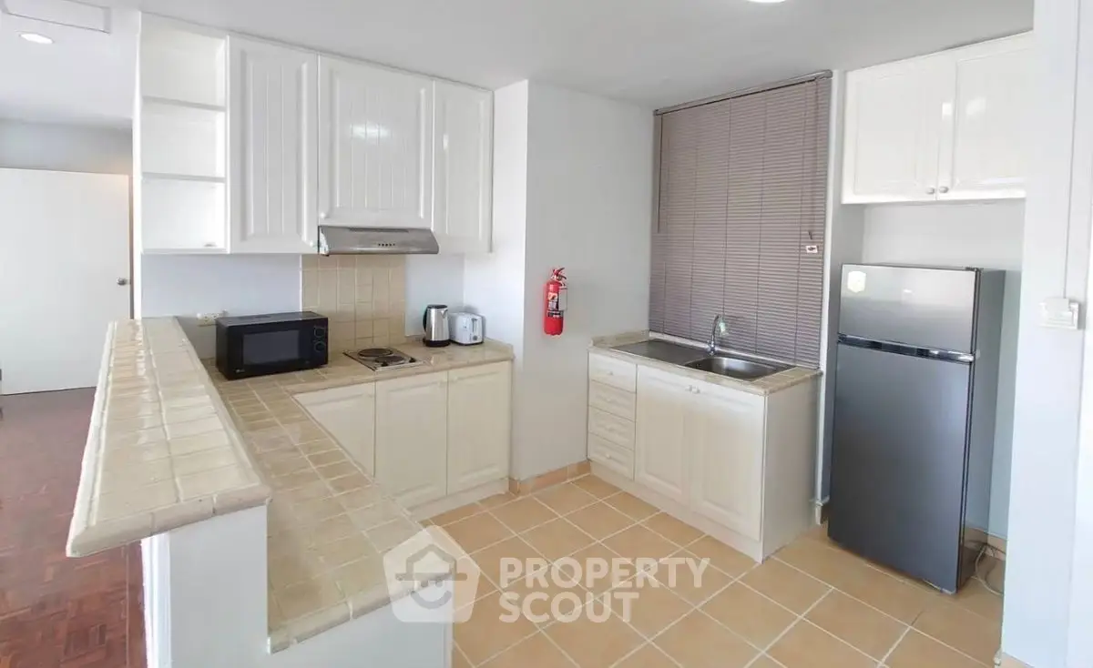 Charming kitchen with modern appliances and tiled countertops, perfect for culinary enthusiasts.