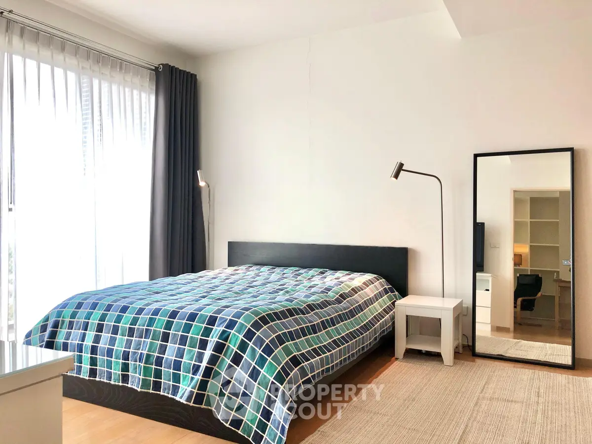Spacious bedroom with modern decor and large window for natural light.