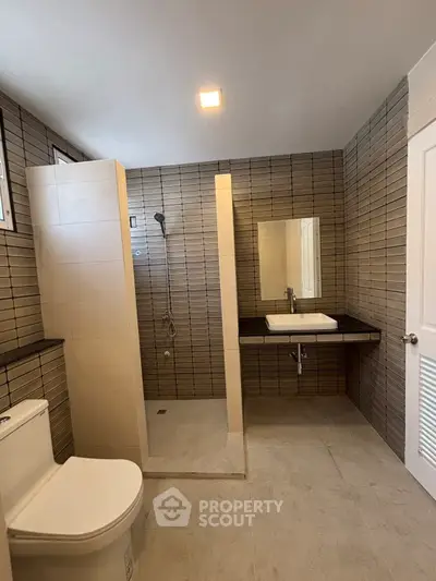Modern bathroom with sleek tiles and walk-in shower in a contemporary home.