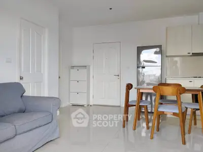 Modern living room with dining area and kitchen featuring sleek furniture and neutral tones.